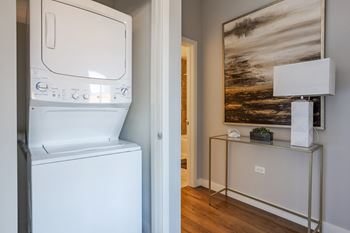 a laundry room with a washer and dryer and a table with a lamp